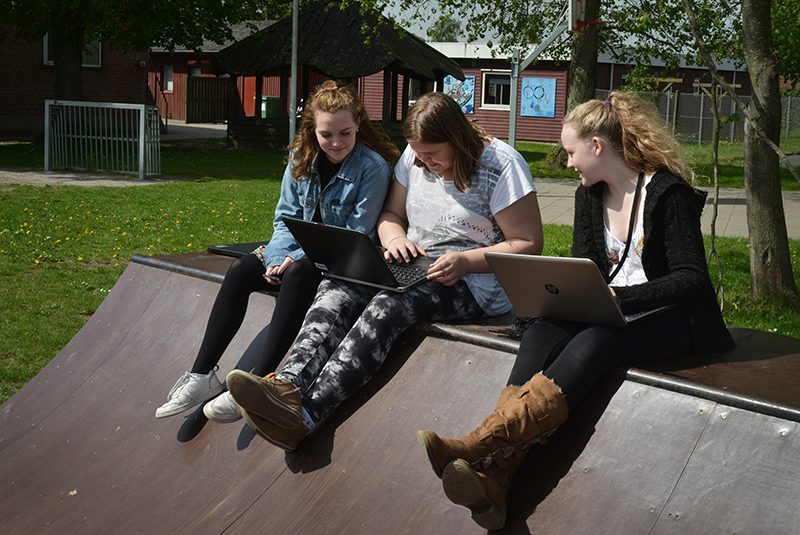 Teenagebørn der sidder og laver skolearbejde på en skaterrampe