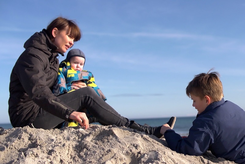 Familie i Norddjurs på en strand En familie sidder på en strand i Norddjurs